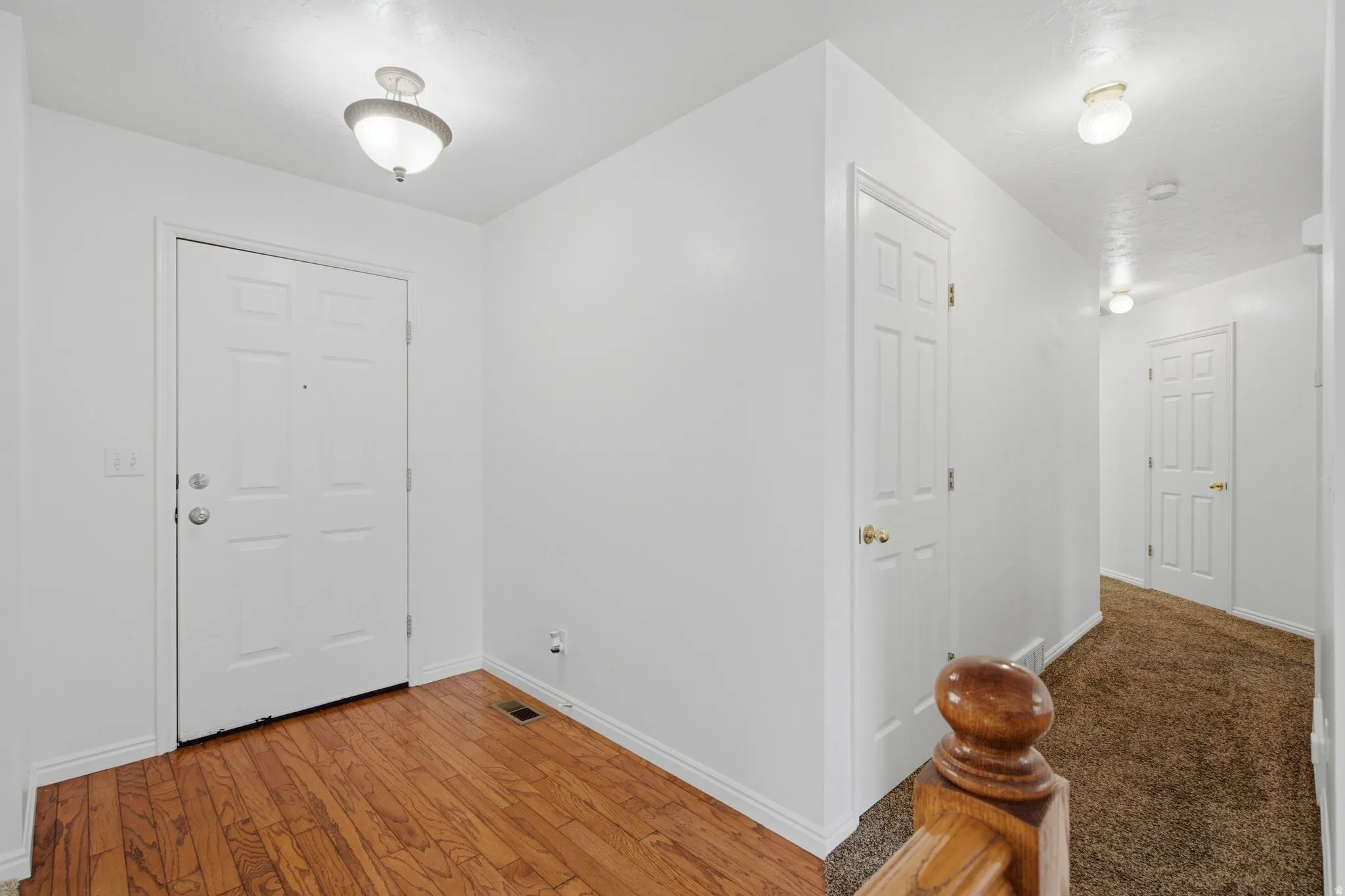 Entryway featuring wood-finish flooring, a white paneled entry door, and a flush mount light fixture
