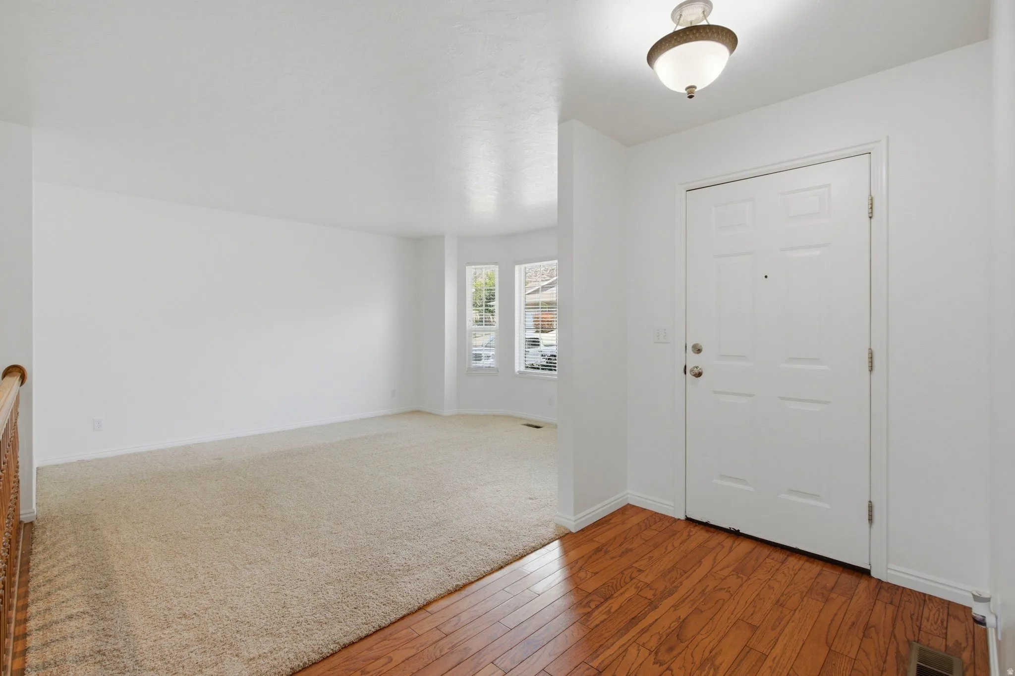 Entryway with wood-finish flooring, a paneled front door, and an overhead light fixture