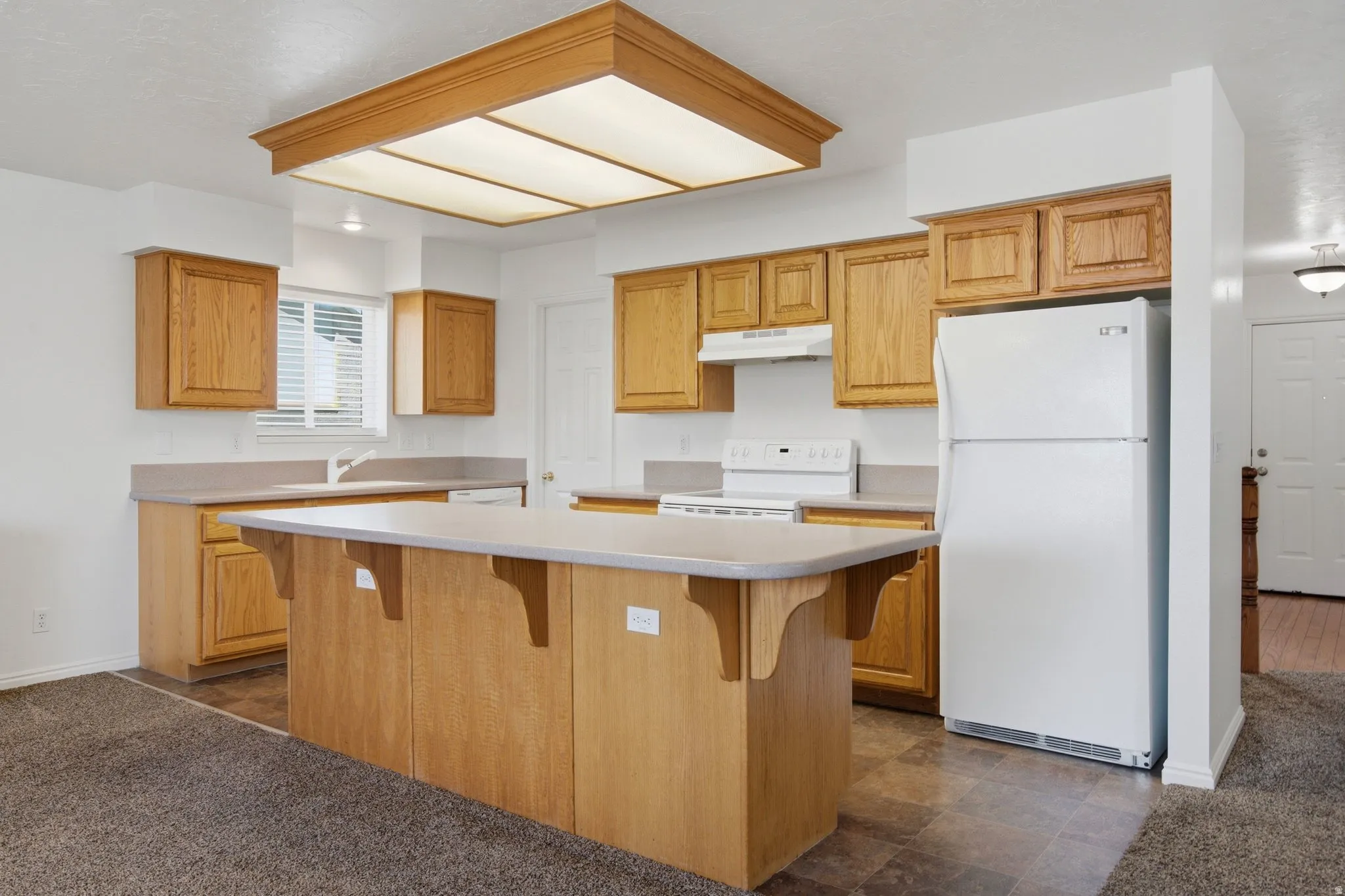 Kitchen featuring wood cabinetry, an island with countertop, and a built-in range with hood