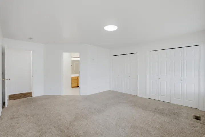 Carpeted room featuring multiple bi-fold closet doors and a ceiling skylight