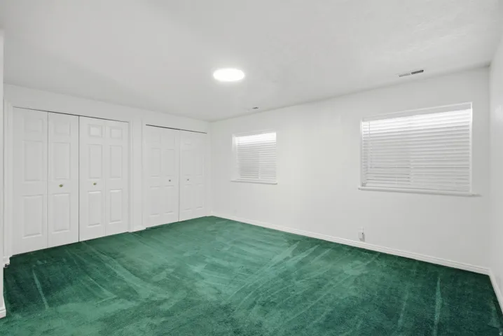 Dual white bi-fold closets, two separate windows with blinds, and recessed lighting