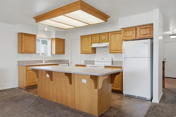 Kitchen featuring wood cabinetry, an island with countertop, and a built-in range with hood