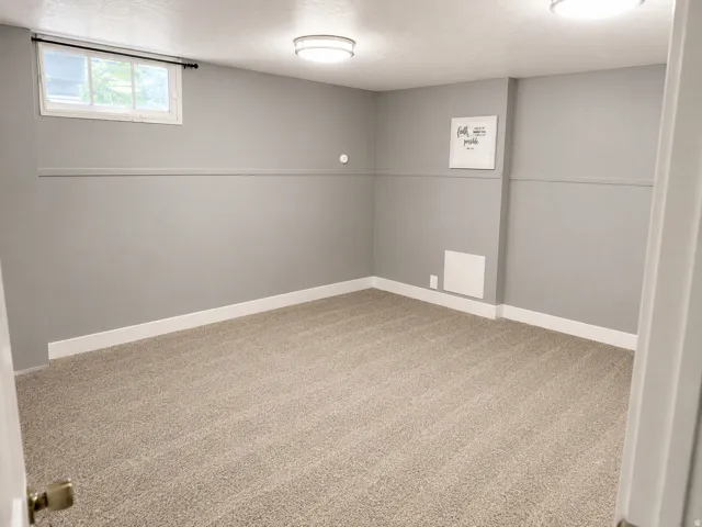 Recessed window, neutral-toned walls, overhead flush mount lighting, and wall-to-wall carpeting