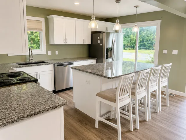 Kitchen featuring white cabinetry, granite countertops, stainless steel appliances, wood-finish flooring,