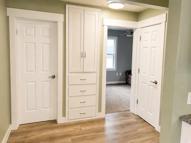 Wood-finish flooring with white trim, built-in cabinetry, and a flush mount ceiling light