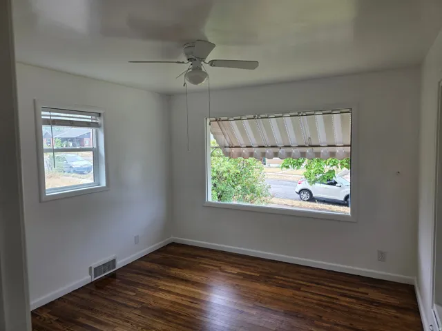 Wood-finish flooring, white walls, and a ceiling fan with integrated lighting