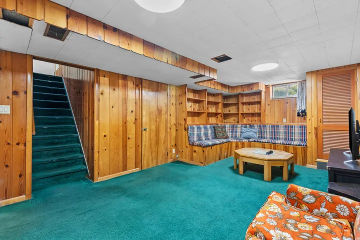Wood-paneled room with built-in shelving, integrated seating, and a window for natural light