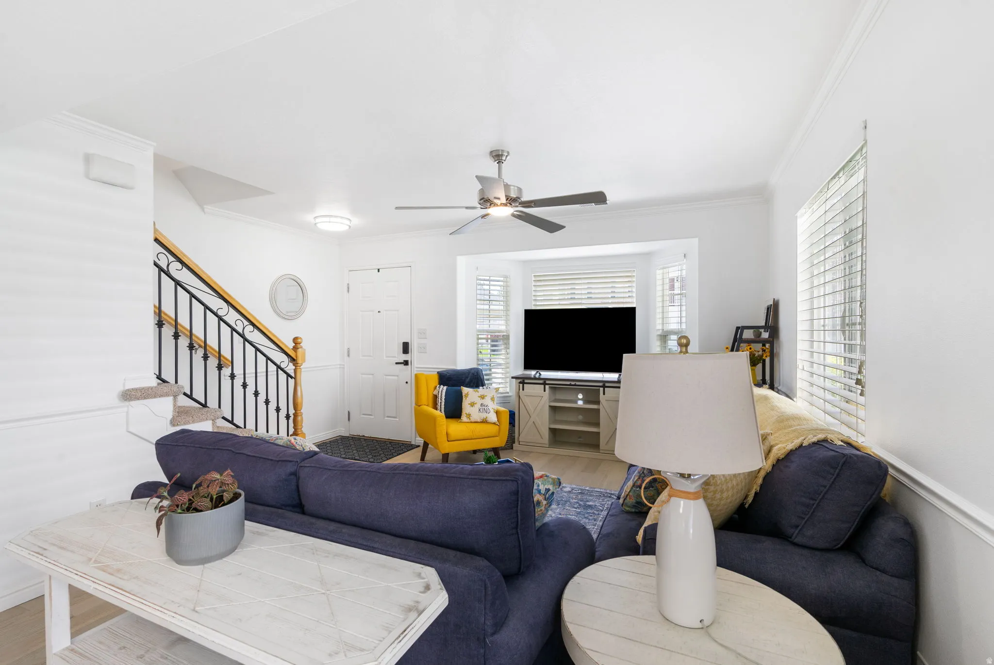 Open-concept living area featuring wood-finish flooring, a contemporary ceiling fan, and a bay window