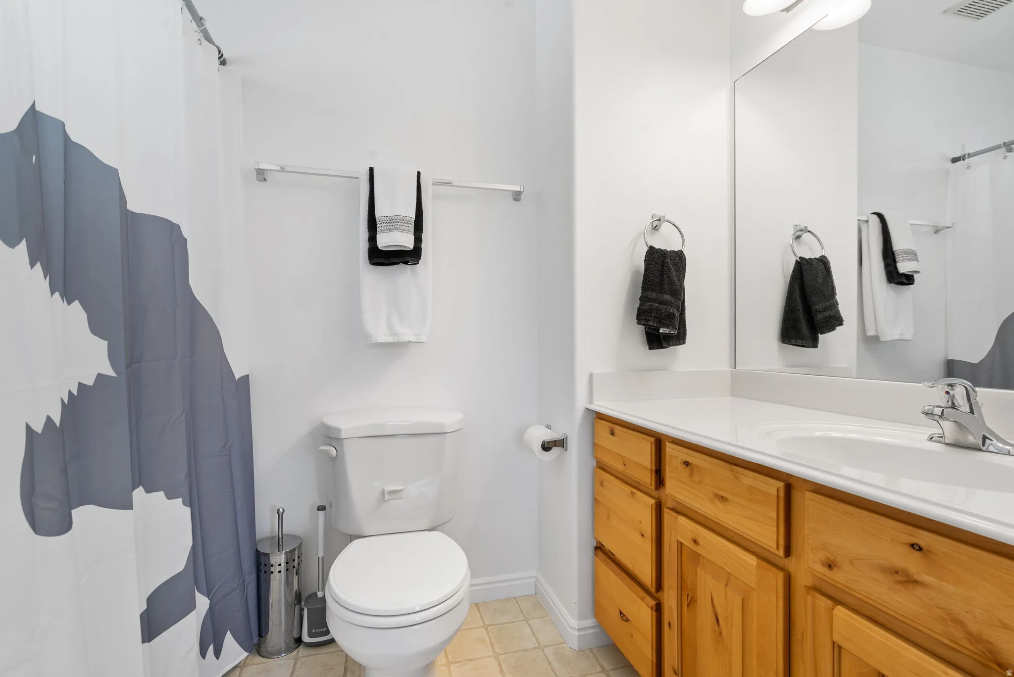 Bathroom featuring a single vanity with wood-finish cabinetry, a white countertop, and a white toilet