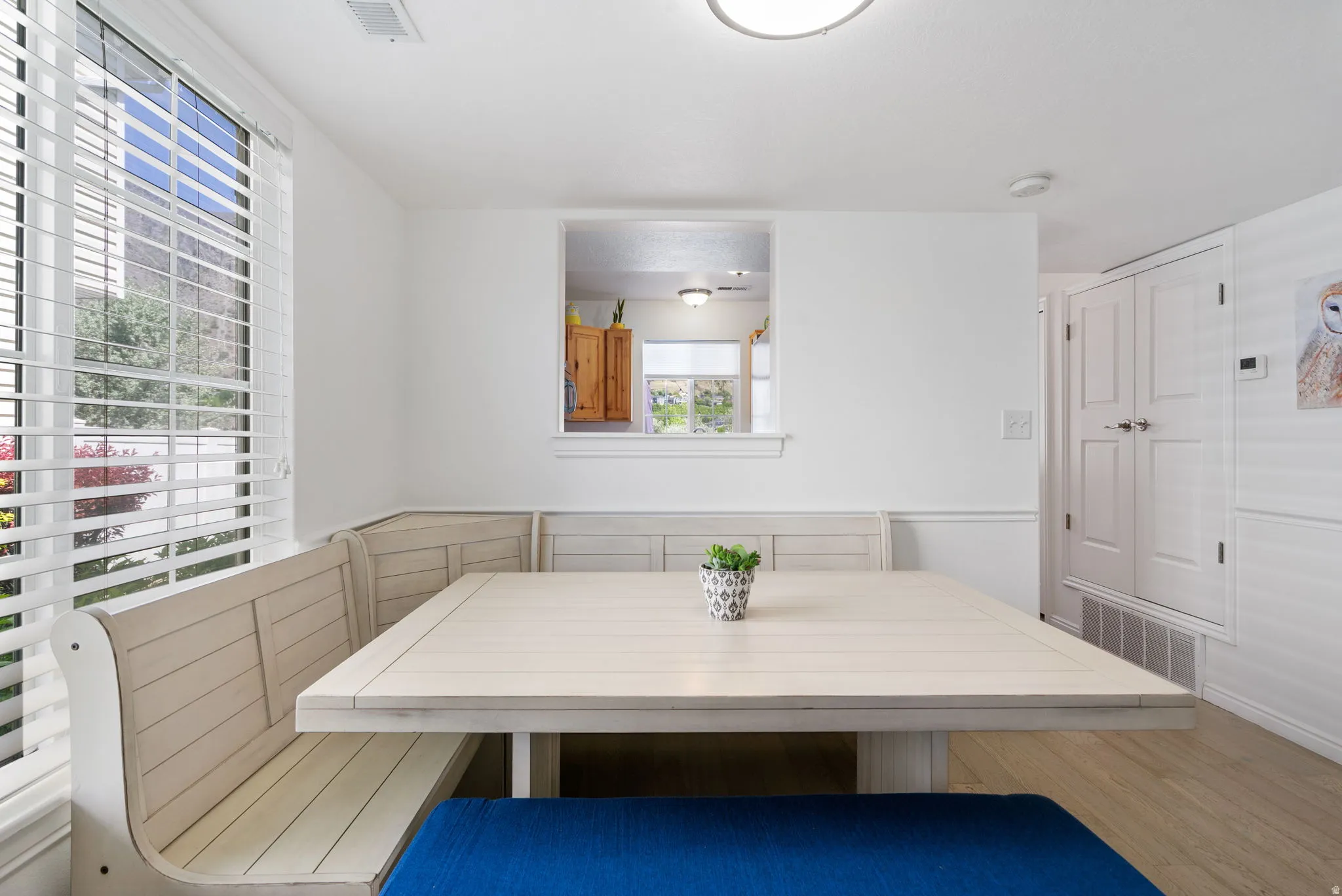Built-in dining nook with light wood-finish seating, large window with blinds, and pass-through opening
