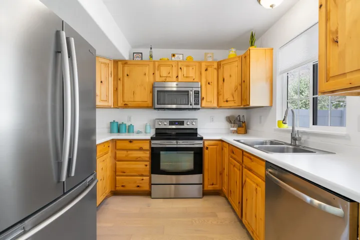 U-shaped kitchen with wood cabinetry, stainless steel appliances, and white countertops
