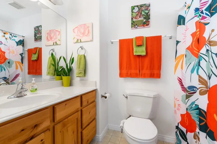 Wood-finish vanity with an integrated sink and light-toned countertop, complemented by a mirror and overhead lighting