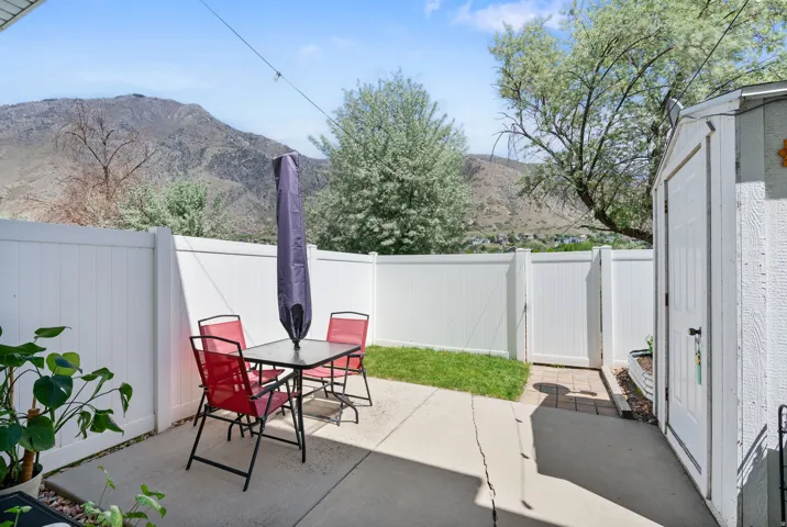 Private patio retreat featuring a composite deck, mature landscaping with established trees, and mountain backdrop