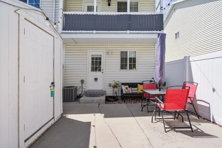 Paved patio area, white privacy fencing, and exterior storage shed
