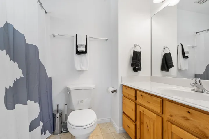 Bathroom featuring a single vanity with wood-finish cabinetry, a white countertop, and a white toilet