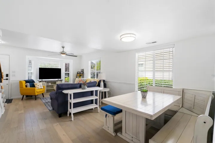 Light wood-finish flooring, white walls, and a ceiling fan