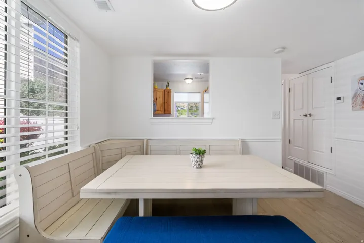 Built-in dining nook with light wood-finish seating, large window with blinds, and pass-through opening