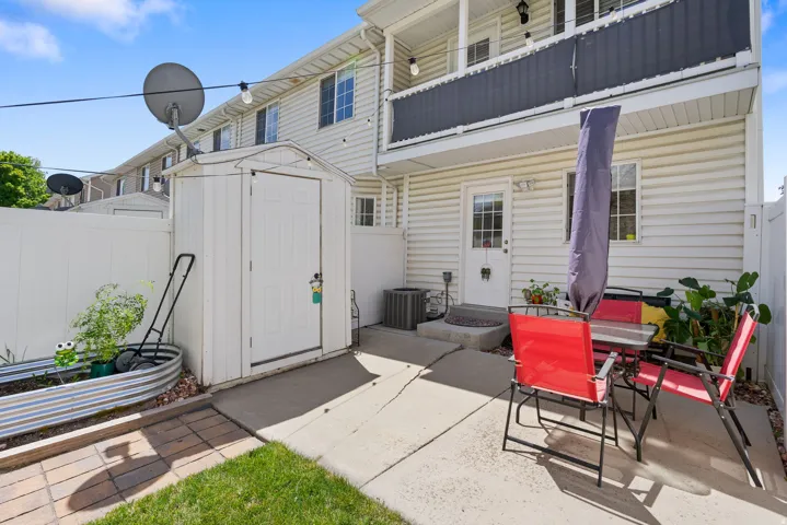 Private patio with concrete surfacing, white privacy fencing, and a storage shed