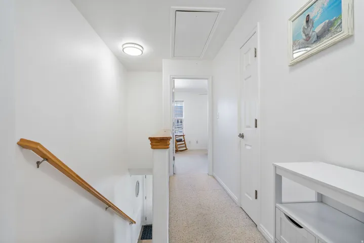 Light-colored carpeting, white walls, and a wood handrail