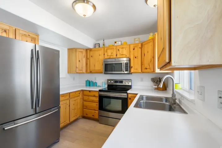 Kitchen featuring wood cabinetry, stainless steel appliances, white countertops, and a double basin sink