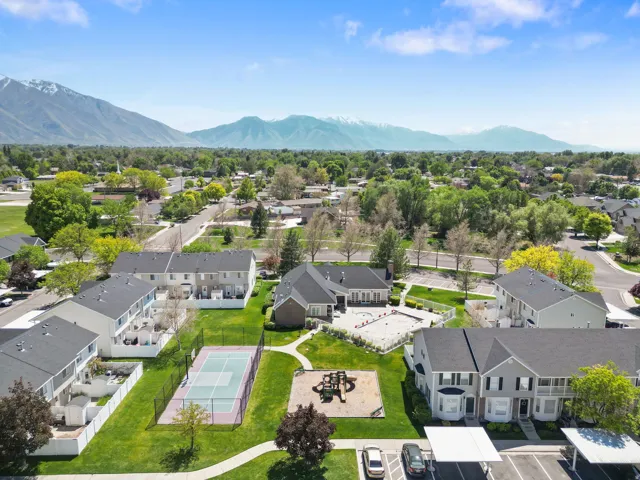 Community green space featuring a tennis court, playground, and paved walking paths