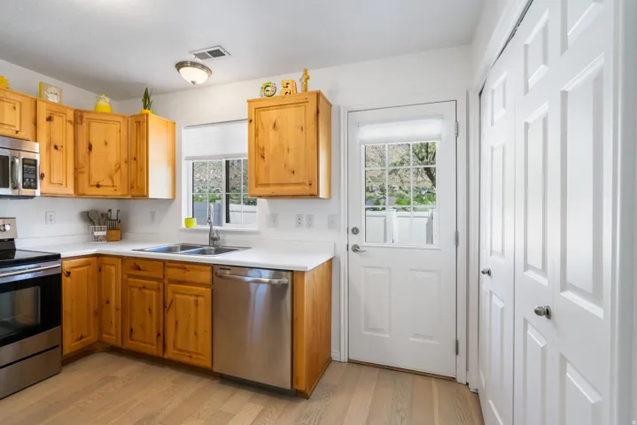 Kitchen featuring wood-finish cabinetry, stainless steel appliances, and wood-finish flooring