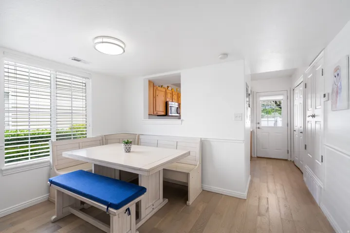 Built-in dining nook, wood-finish flooring, white paneled doors, pass-through window to kitchen, contemporary flush mount ceiling light