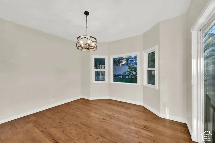 Bay window with multiple panes, wood-finish flooring, contemporary chandelier, and a sliding glass door