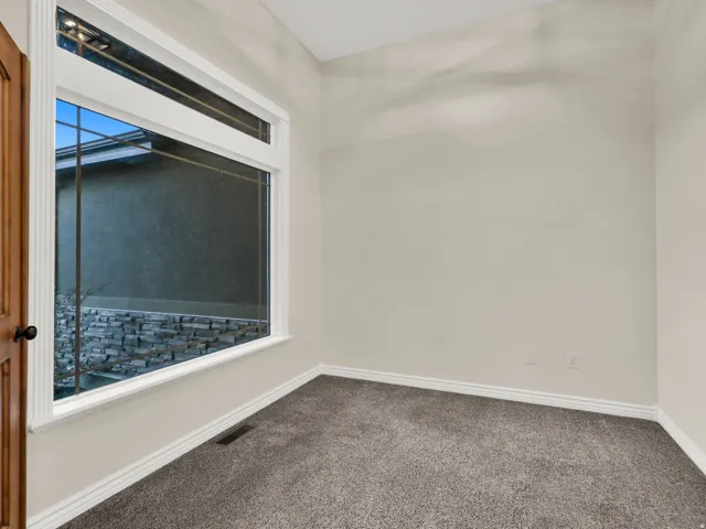 Wall-to-wall carpeting, light neutral wall paint, and a large window with white trim