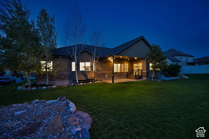 Expansive backyard featuring a stone rock garden and a covered patio with recessed lighting