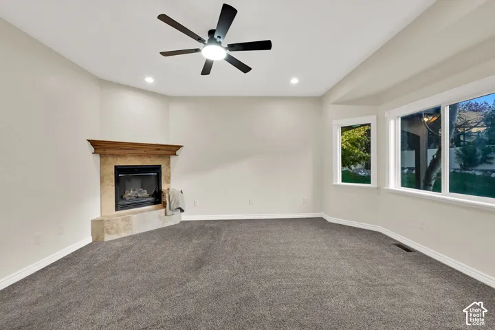 Living space featuring a natural stone fireplace with a wood mantel, a multi-pane bay window, recessed lighting, and a ceiling fan