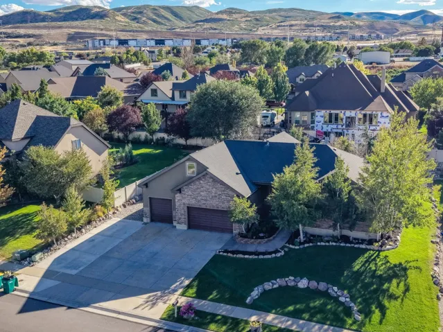 Stone and stucco exterior residence featuring an attached two-car garage, mature landscaping, and a manicured lawn