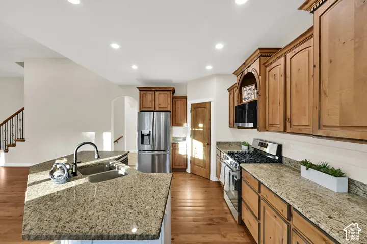Kitchen featuring granite countertops, wood cabinetry, stainless steel appliances, and wood-finish flooring
