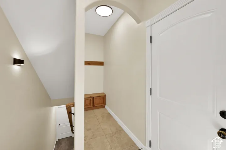Recessed lighting, arched entryway, wood-finish built-in storage, tile flooring, and a paneled interior door