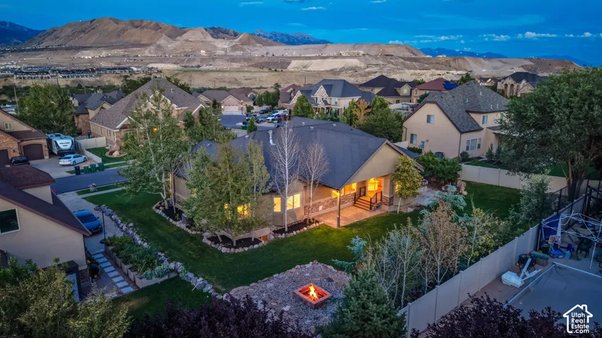 Expansive backyard featuring a fire pit, mature landscaping, and a covered patio