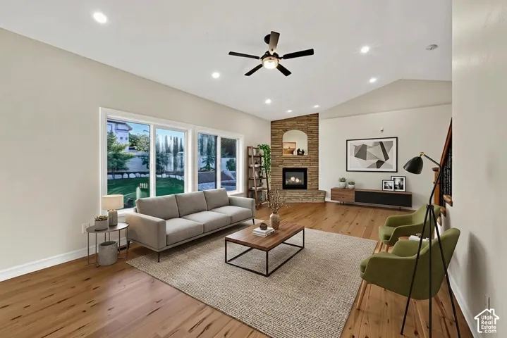 Vaulted ceiling, recessed lighting, wood-finish flooring, stone-accented fireplace with built-in mantel, and expansive windows