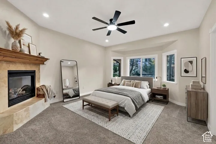 Vaulted ceilings, a stone-clad fireplace with a wood mantel, a ceiling fan with integrated lighting, recessed lighting, and a bay window