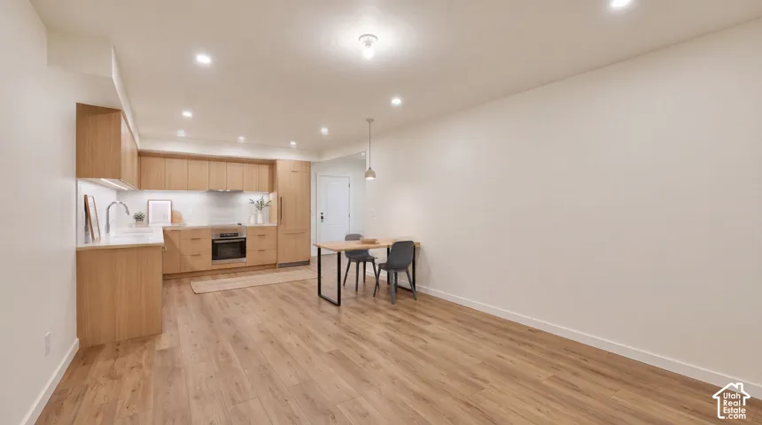 Contemporary kitchen featuring wood-finish cabinetry, light-toned countertops, and a subway tile backsplash