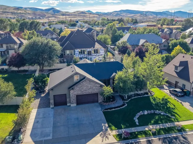 Exterior featuring a two-car garage, stone and stucco facade, and a well-maintained lawn with mature landscaping