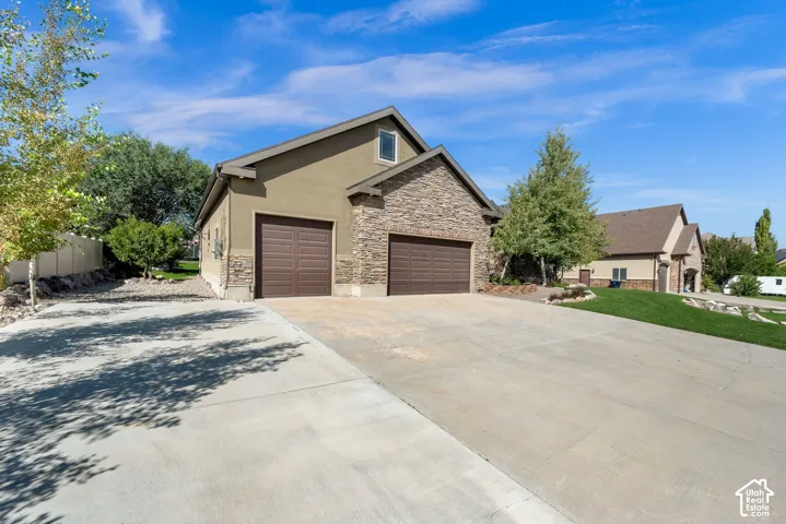 Stucco and stone exterior with a two-car attached garage and an additional single-car attached garage
