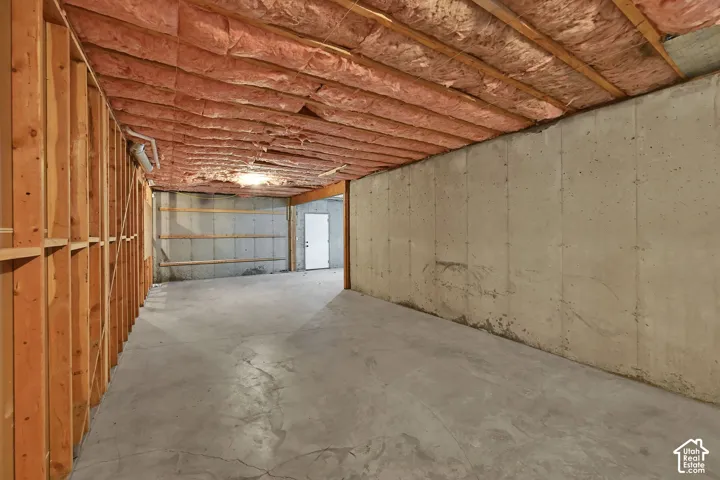 Unfinished basement with exposed wood framing, concrete floor, and concrete walls