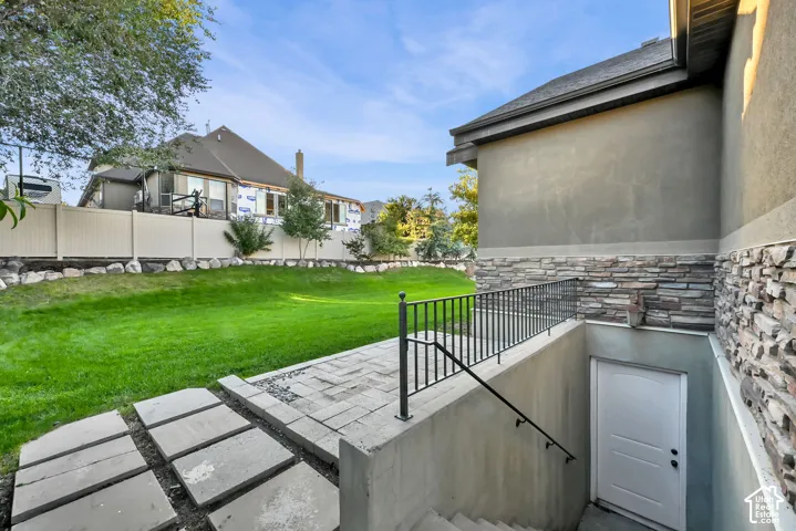Expansive grassy yard with tiered landscaping and a privacy fence