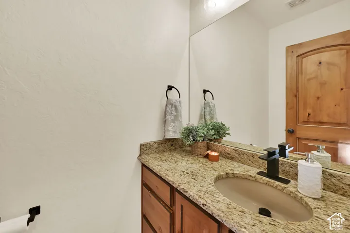 Vanity featuring a stone-finish countertop, undermount oval sink, and a matte black single-handle faucet