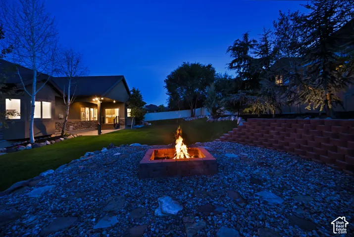 Built-in fire pit with brick surround, gravel hardscaping, and a terraced retaining wall