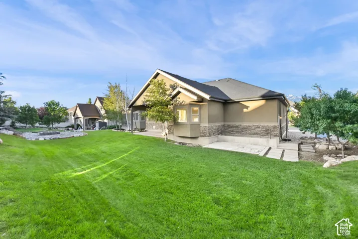 Expansive green lawn with a structured stone border and a paved walkway leading to the home's stucco and stone exterior