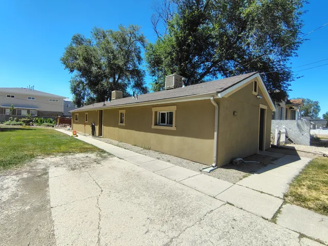 Stucco exterior with multiple windows, a gabled roof, and a concrete pathway