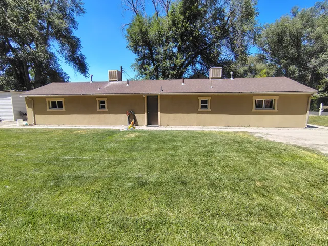 Stucco exterior with multiple windows, a central entry door, and a brown shingle roof