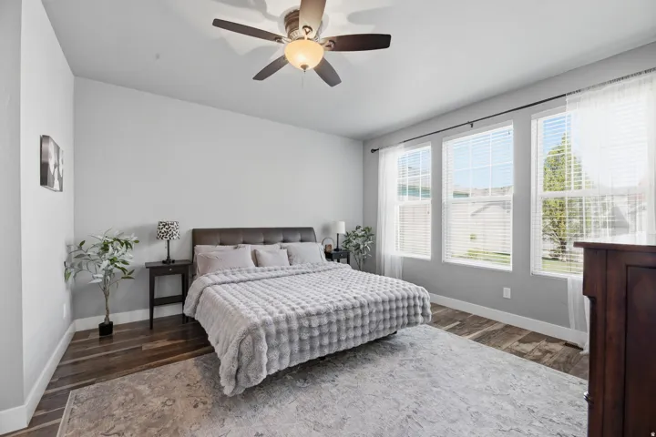 Vaulted ceilings with a ceiling fan, three large windows with white blinds, and wood-finish flooring