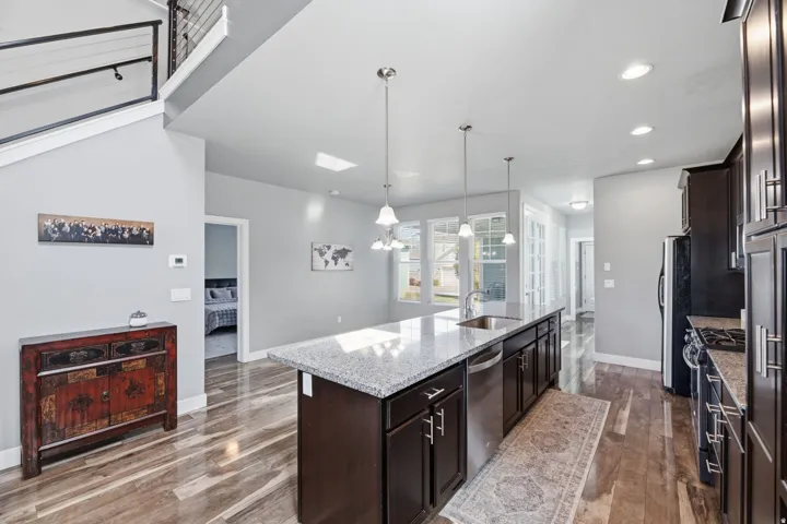 Kitchen island with a granite countertop, stainless steel sink, and pendant lighting