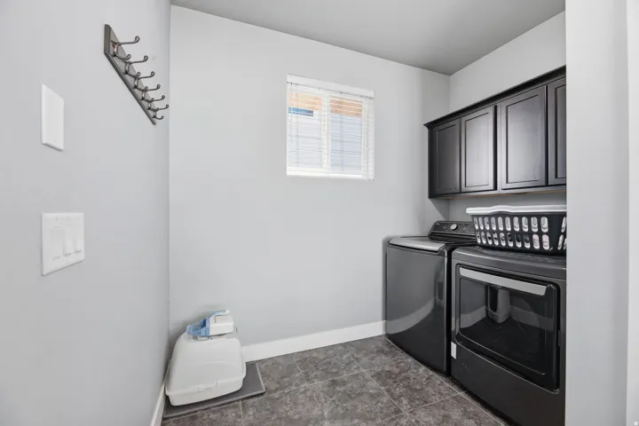 Laundry area featuring dark cabinetry, window with blinds, and tile flooring